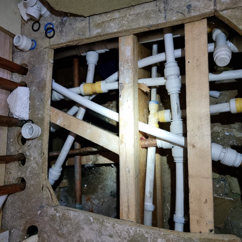 Exposed leaking pipework being repaired by plumber in Bletchley